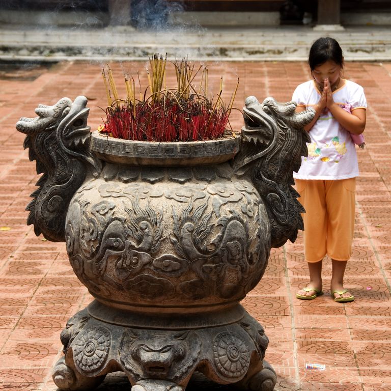 Vietnam - Girl praying in the temple Do (Quan Ho)